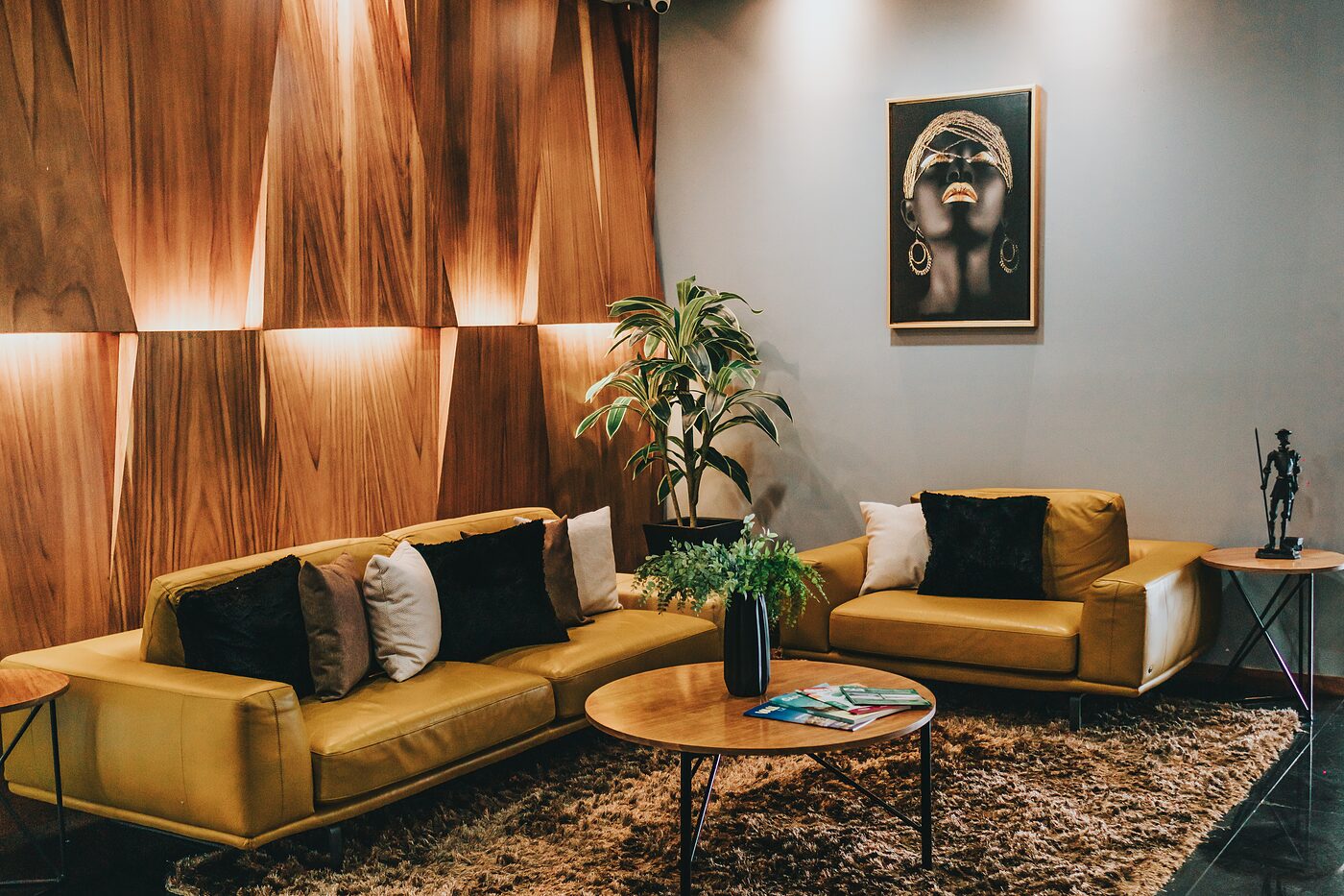 Sala de espera con sofás amarillos, muro de madera texturizada y obra enmarcada
