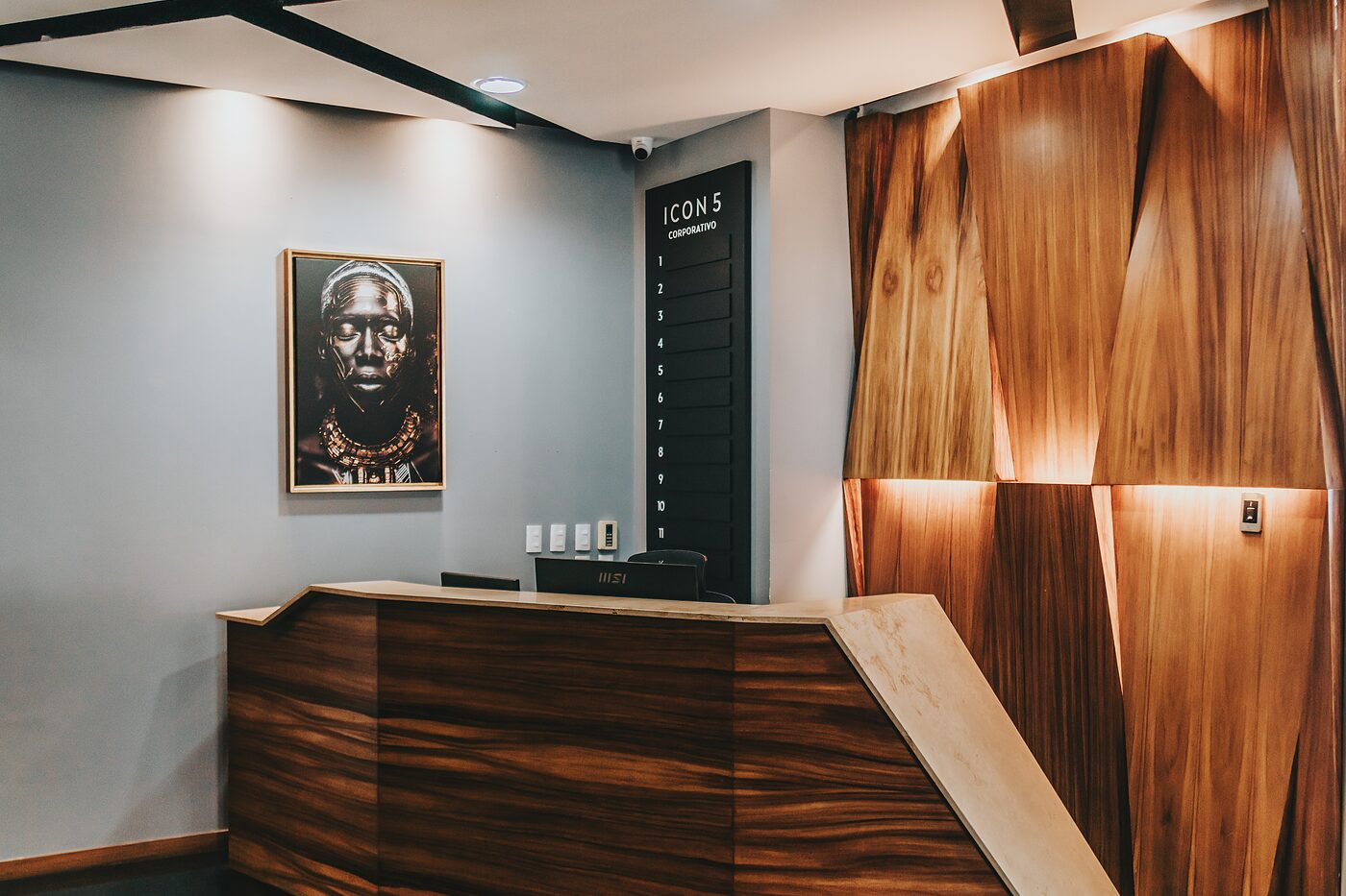 Mostrador de recepción del Piso 5 en madera veteada, con el directorio de Icon5
