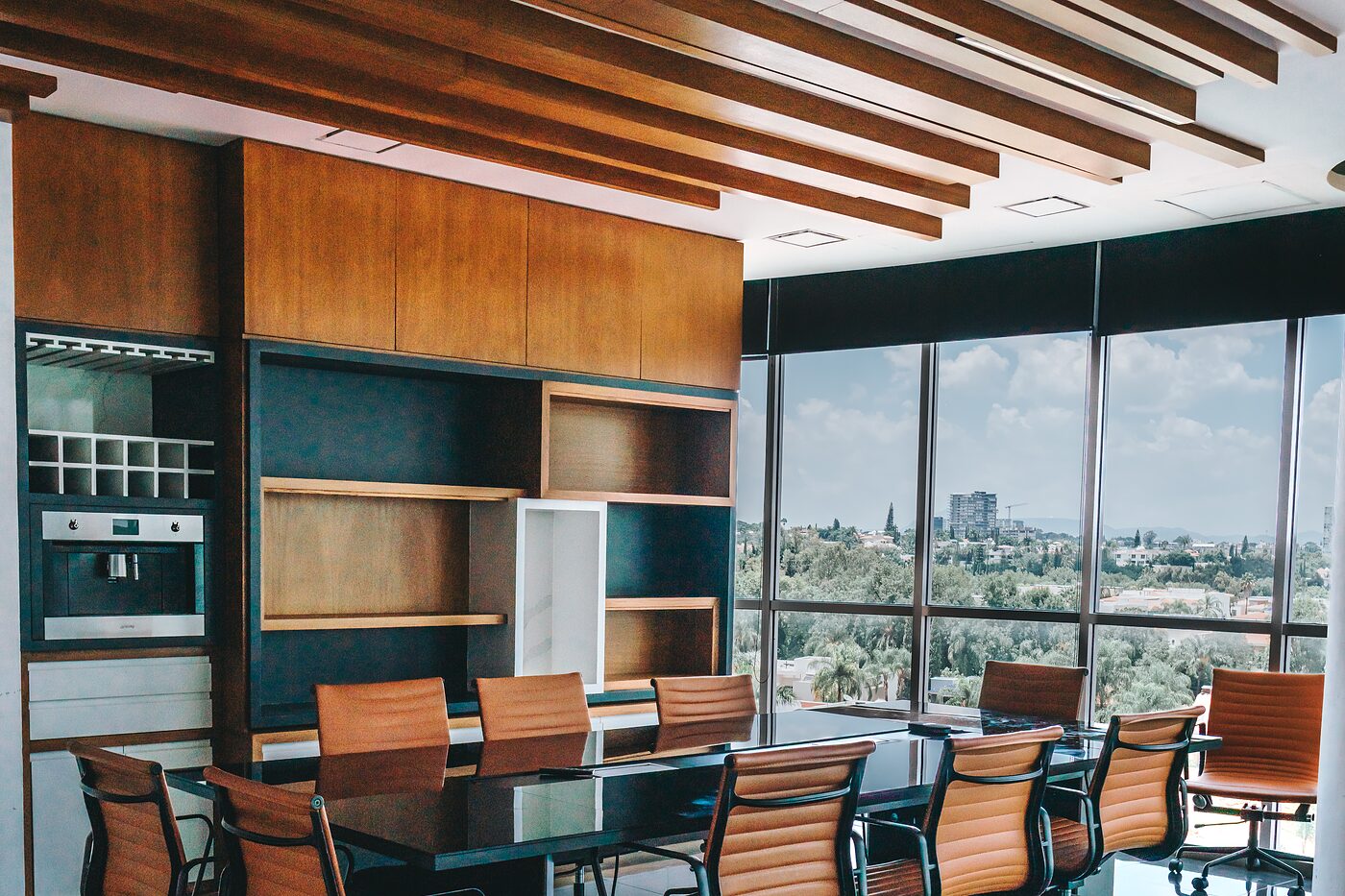 Sala de juntas con techo de vigas de madera, sillas de piel cognac y ventanal panorámico